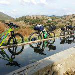 Edizione di settembre 2016 del Sardinia Divide. Bici all’abbeverata mentre il gruppo vista le domus de janas di Asuni