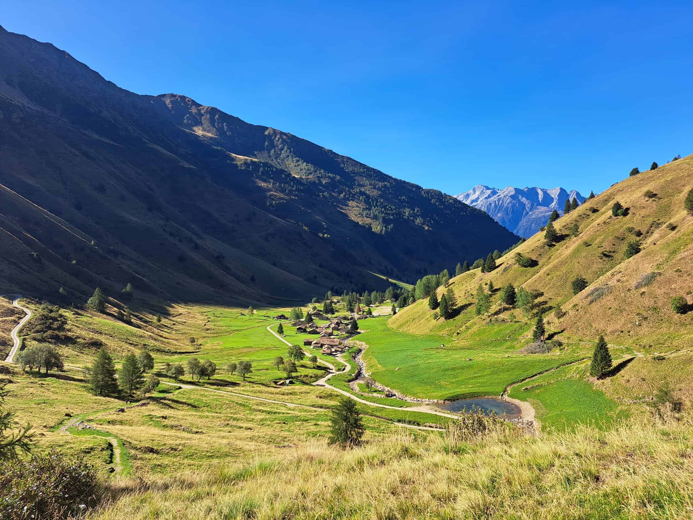 Valle di montagna con baite e laghetto